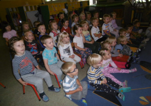 Dzieci 3 i 4 letnie siedza na krzesełkach i oglądają przedstawienie 'Kozucha kłamczucha"
