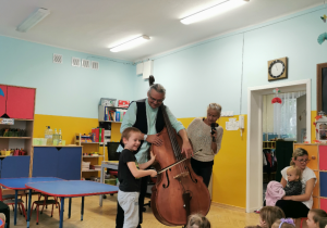 Chłopiec z pomocą muzyka próbuje grać na instrumencie.