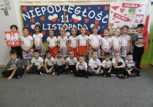 Zdjęcie grupowe dzieci z grupy 5 w strojach biało-czerwonych, na tle tablicy z napisem Niepodległość 11 Listopada