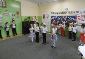 Dzieci prezentują flagę i godło Polski.