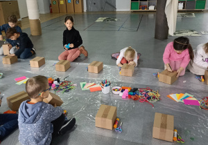 dzieci na sali w muzeum projektują budynek z pudełka , korzystają z przygotowanych różnorodnych materiałów.