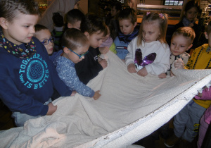Dzieci dotykają materiał utkany z nici.