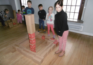 Dzieci w grupach układają model fabryki z tekturowych pudełek.