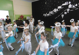 Dzieci z grupy 4 są w stojach biało niebieskich i prezentują taniec z szarfami