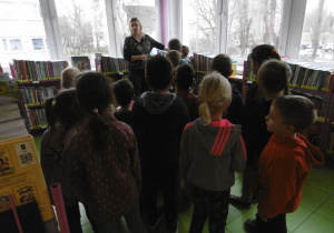 Przedszkolaki znajdują się w pomieszczeniu gdzie na półkach są książki dla najmłodszych.