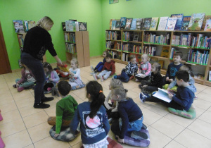 Pani bibliotekarka rozdaje dzieciom książki.