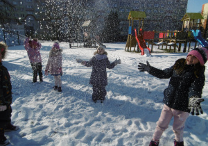 Dzieci podrzucają śnieg do góry.