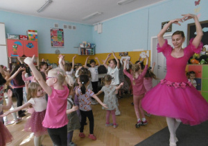 Dziewczynki tańczą piruet pokazywany przez baletnicę w różowej sukience.