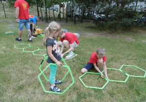 Dzieci na trawie układają tor z sześciokątnych obręczy