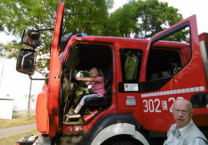 Dziewczynka siedzi w szoferce wozu strażackiego
