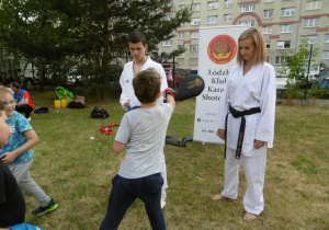 Punkt karate. Chłopiec kieruje cios prawą ręką na paletę trzymaną przez trenera