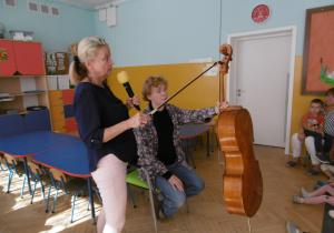 Prezenterka pokazuje dzieciom części składowe wiolonczeli