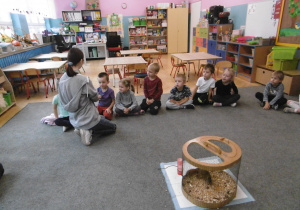 Dzieci z grupy czwartej siedzą w kole. W środku koła stoi klatka z wiewiórką. Prowadząca zajęcia pokazuje dzieciom jeża.