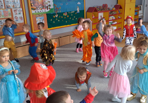 Dzieci z grupy 1 w bajkowych strojach swobodnie poruszają się po sali.