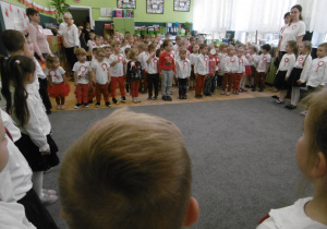 Przedszkolaki w pozycji na baczność śpiewaja hymn państwowy