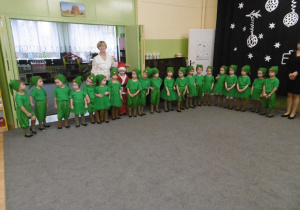 Dzieci elfy stoją w szeregu, za nimi stoi nauczycielka.