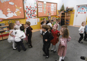 Przedszkolaki w uroczystych strojach tańczą w czterech kołach.