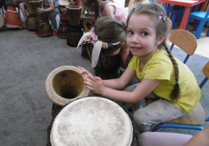 Dziewczynka pokazuje wnetrze bębna djembe.