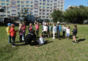 Grupa przedszkolaków przygotowuje się do zabawy ruchowej z piłkami.