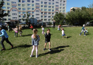 Przedszkolaki biegają na polance w ogrodzie.