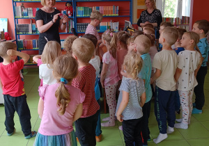 Pani bibliotekarka pokazuje dzieciom kartę biblioteczną.
