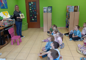Panie bibliotekarki pokazują dzieciom różne rodzaje książek dla najmłodszych.