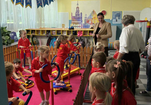 Pani wiceprezydent Łodz i pani dyrektor obserwują trening przedszkolaków w siłowni.