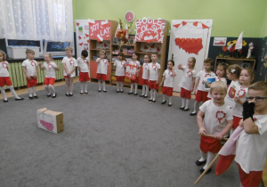 Grupa dzieci wita uczestników uroczystości.