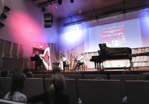 Trzy harfistki grają na harfach.