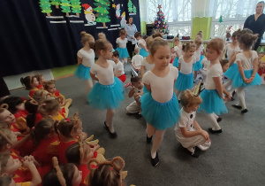 Zabawki-laleczki tańczą wokół pajacyków.