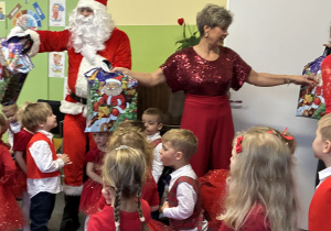 Mikołaj i pani dyrektor rozdają dzieciom prezenty.