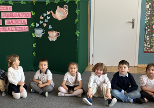 Grupa dzieci siedzi na dywanie.