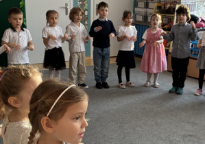 Grupa dzieci stoi na scenie w półkolu.