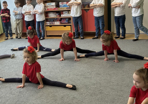 Grupa dziewczynek wykonuje szpagat.